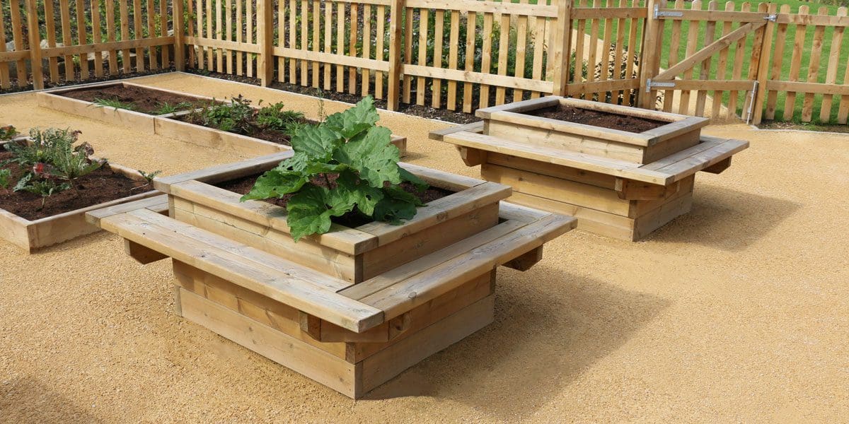 Rows of long raised plant beds and taller square planters with attached seating