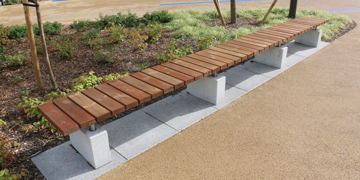 Long outdoor wooden bench with concrete plinth legs