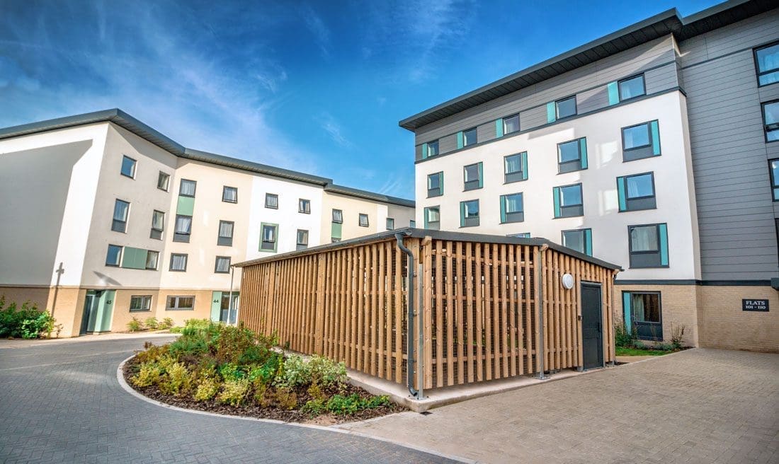 University exterior showing large cycle storage structures infront of tall buildings