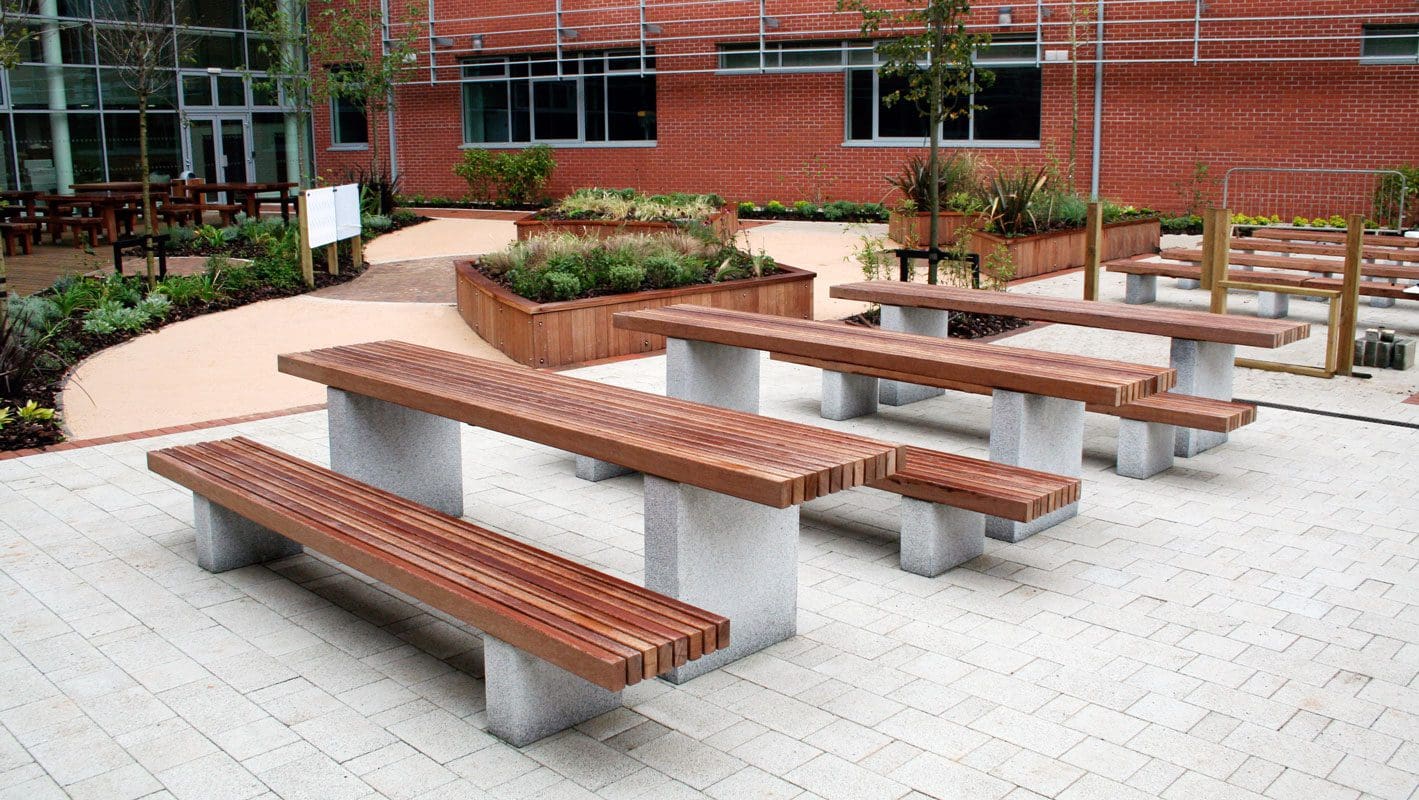 Row of matching wooden slatted tables and benches with concrete plinth legs