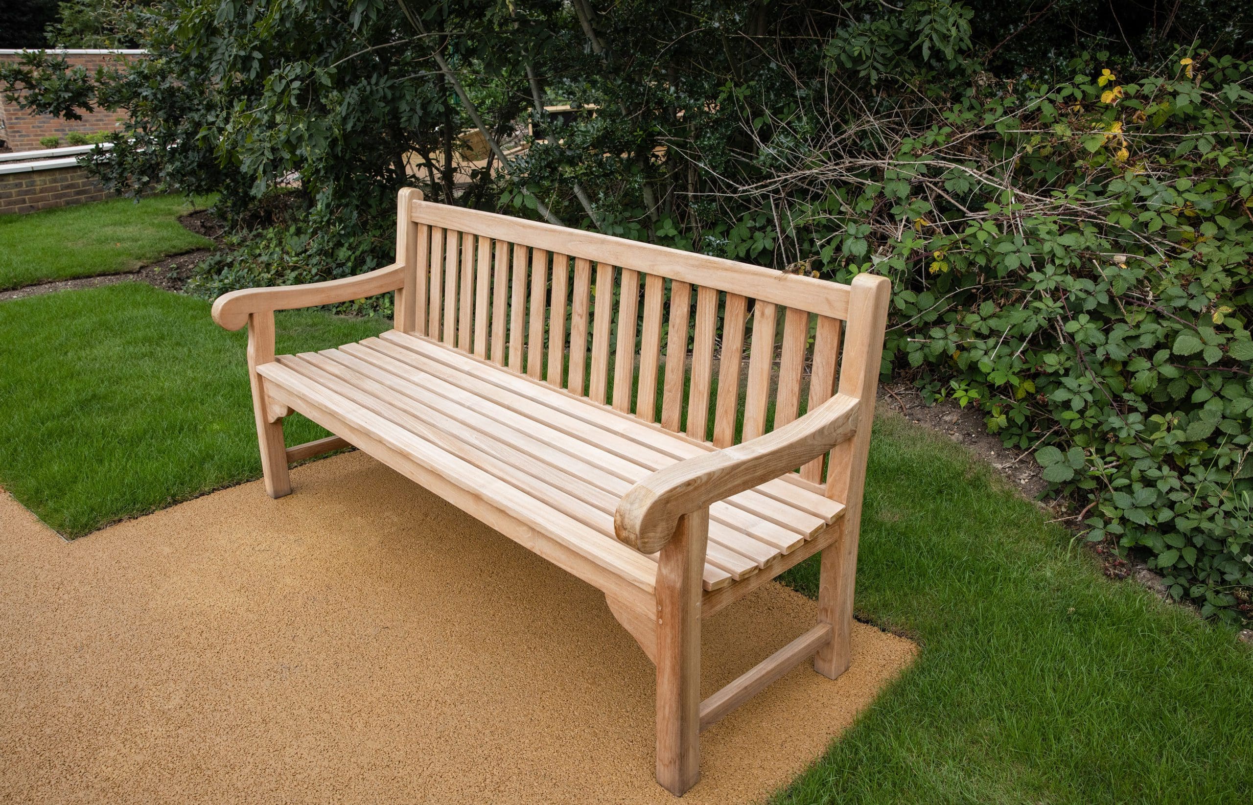 Traditional wooden park bench infront of bush