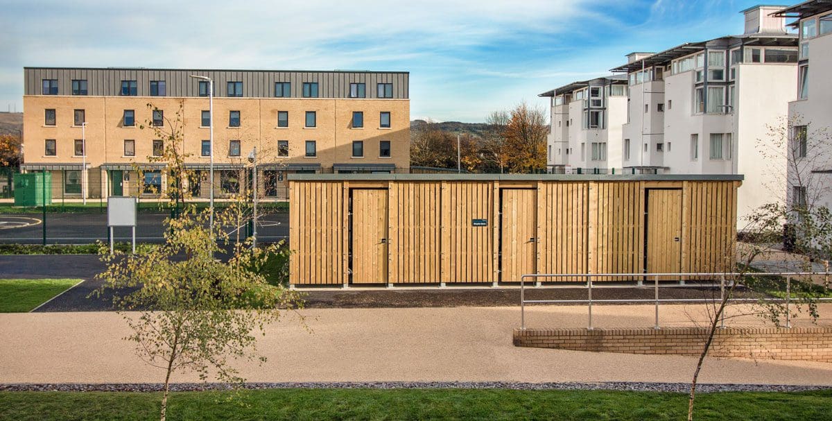 Large outdoor wooden bicycle storage unit infront of university building