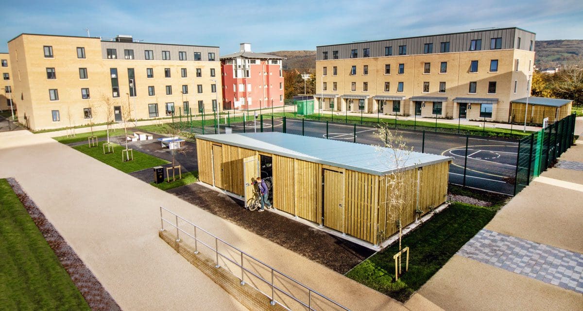 Wide shot of university exteriors with large bicycle storage unit infront of basketball court