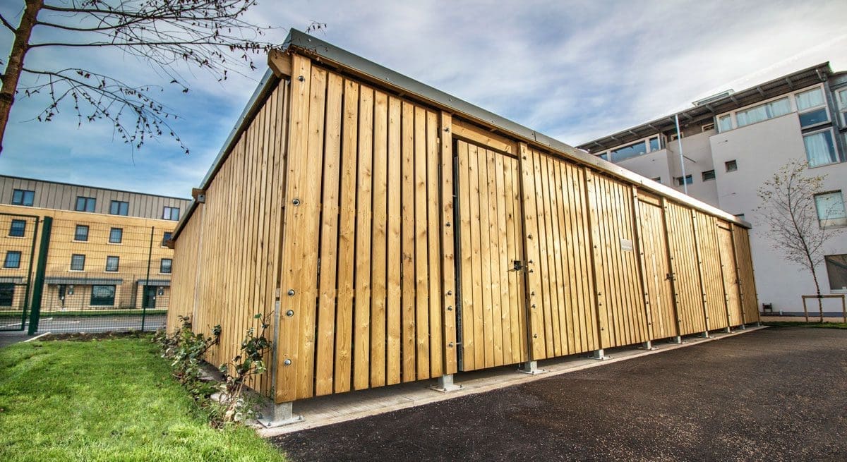 Large outdoor wooden bicycle storage unit infront of university building