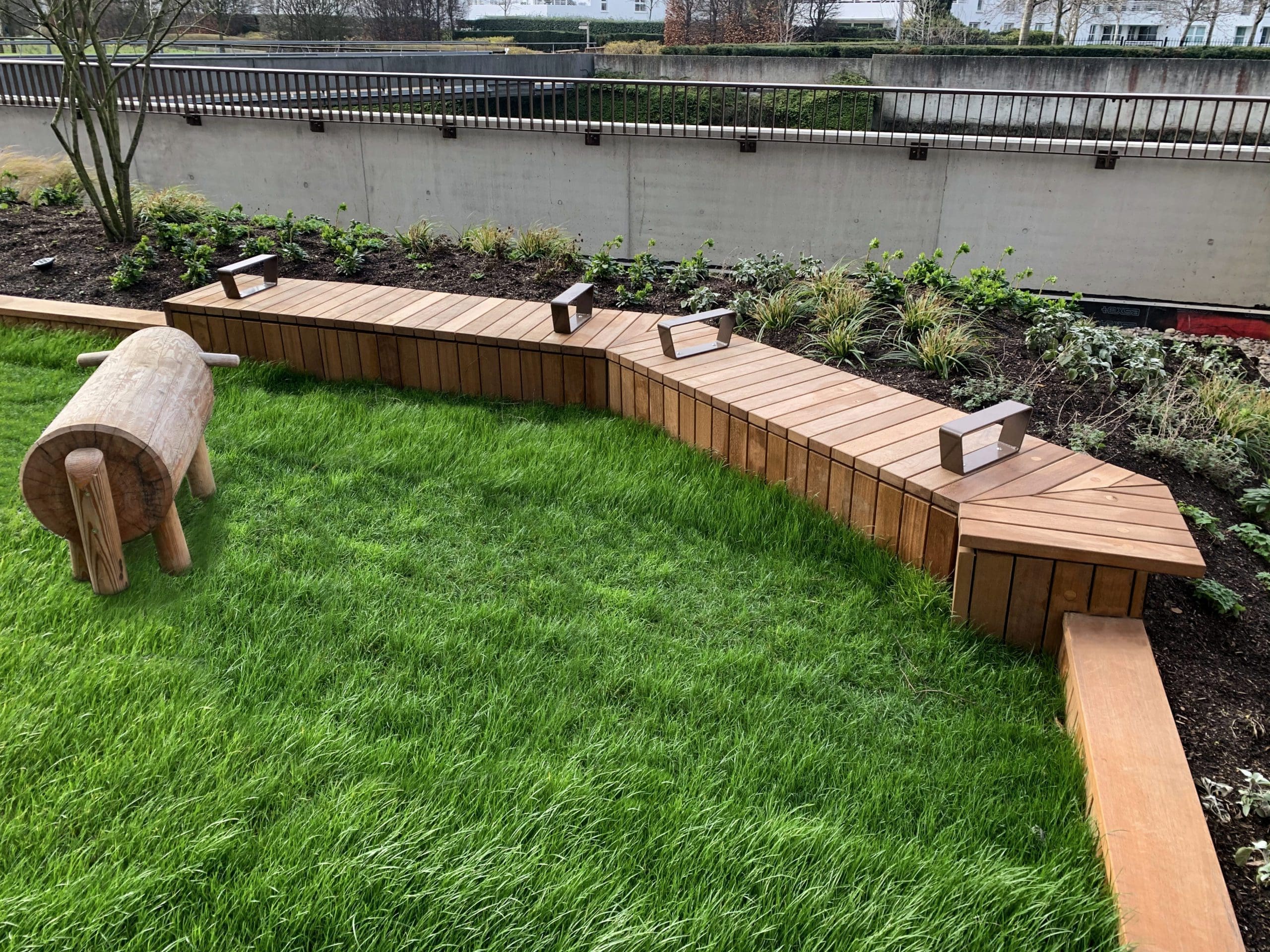 Angled line of wooden timber seating bench with arm rest separators