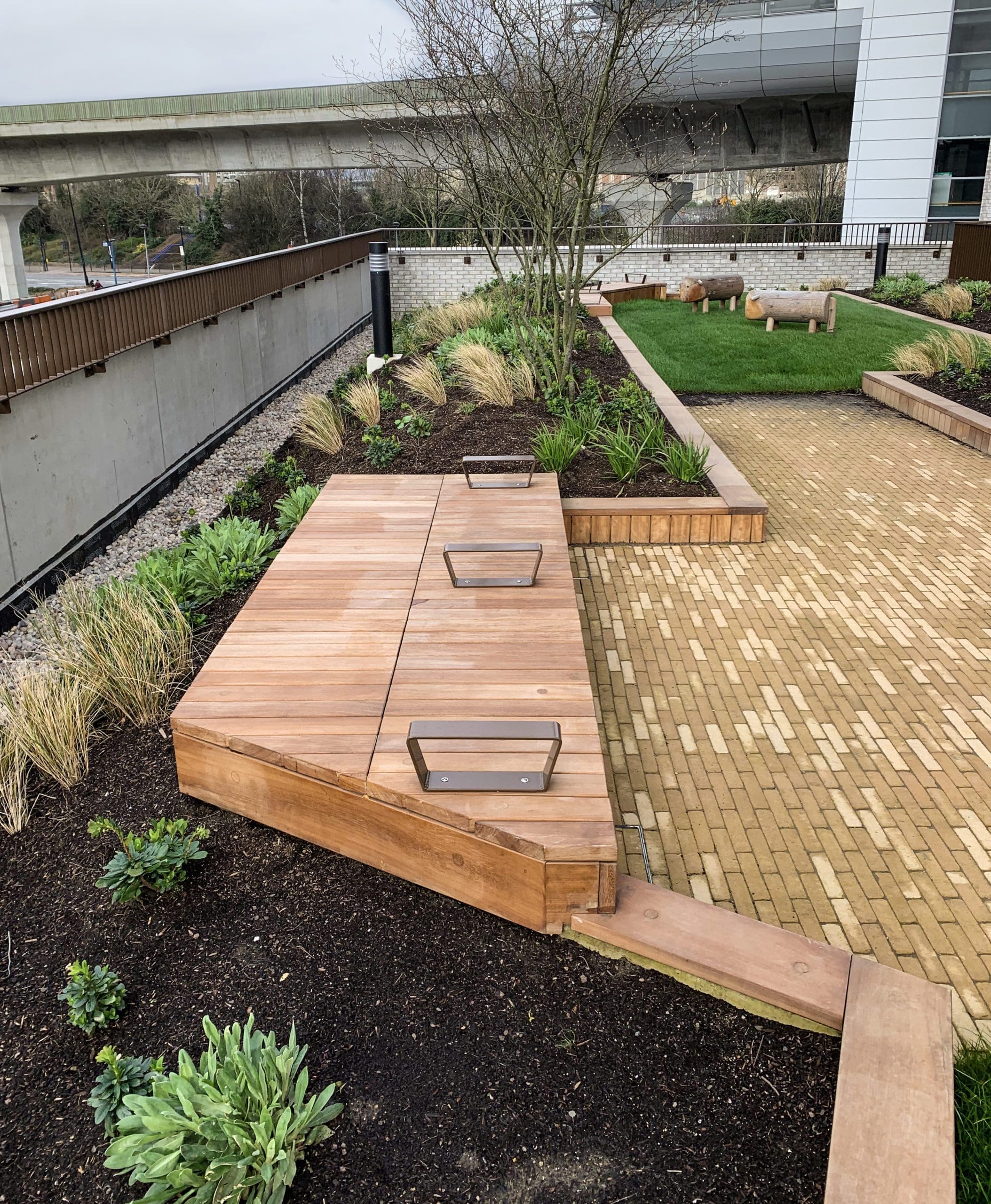 Angled line of wooden timber seating bench with arm rest separators