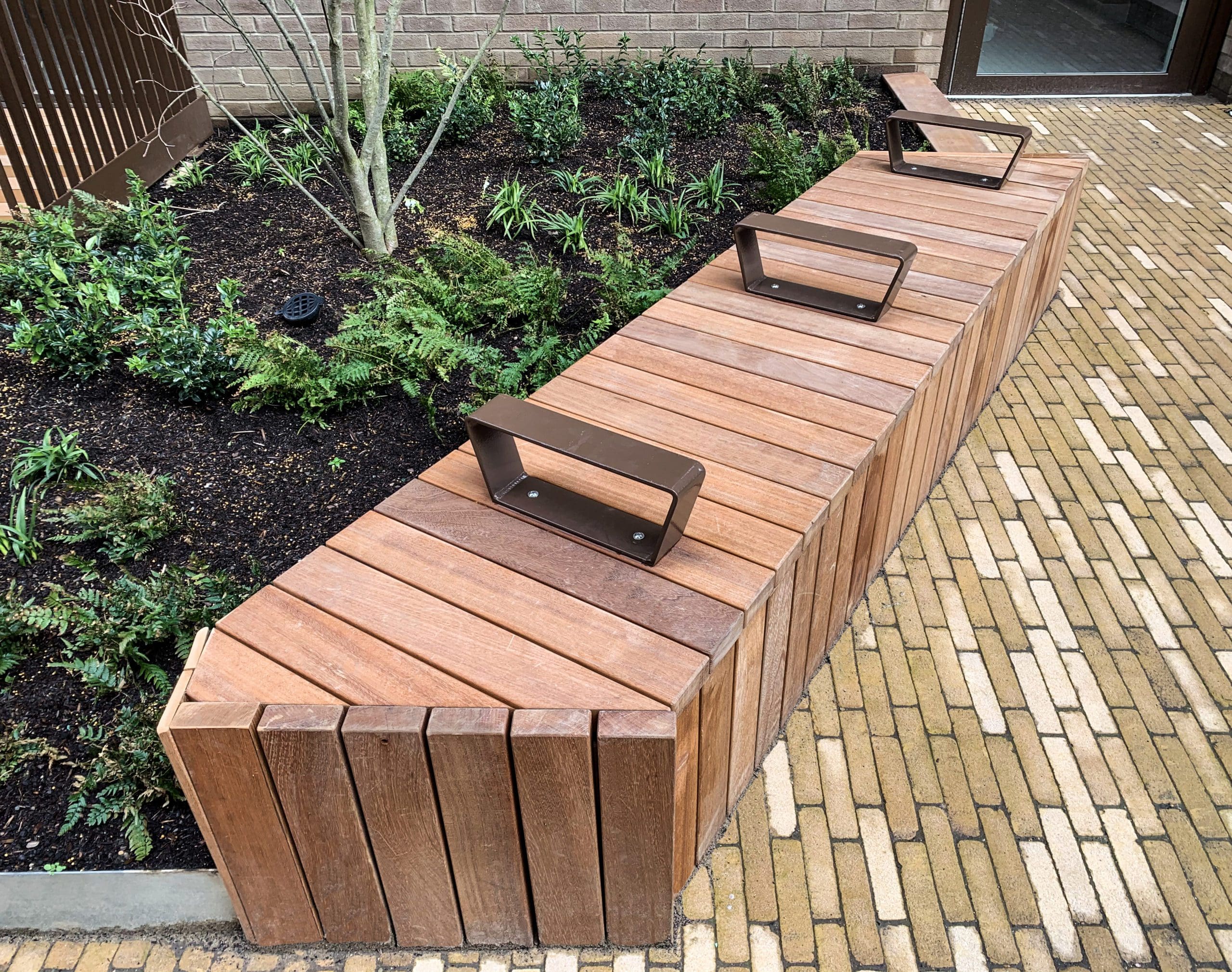 Angled line of wooden timber seating bench with arm rest separators