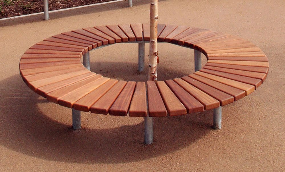 Wooden slatted circle bench with metal legs surrounding small tree