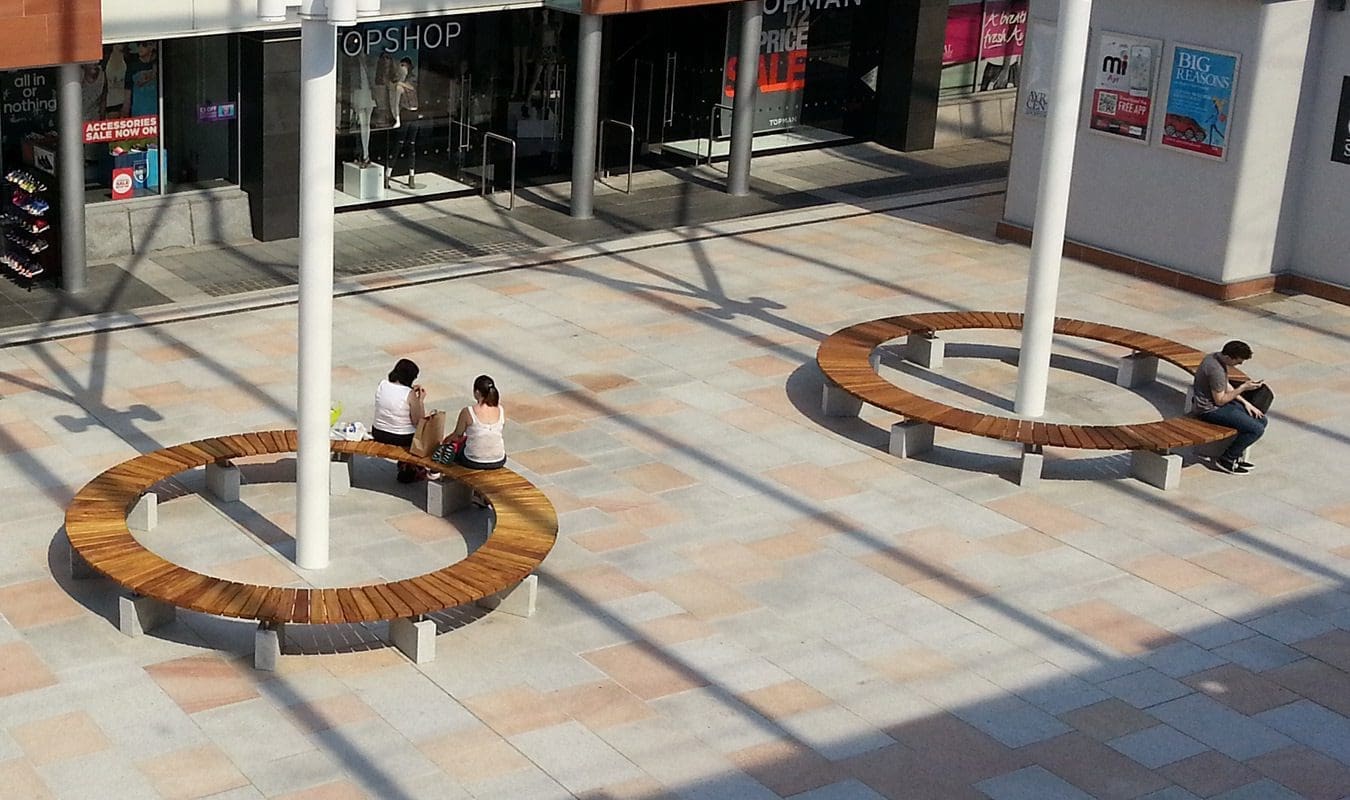 Full circle wooden benches with concrete feet around structural post