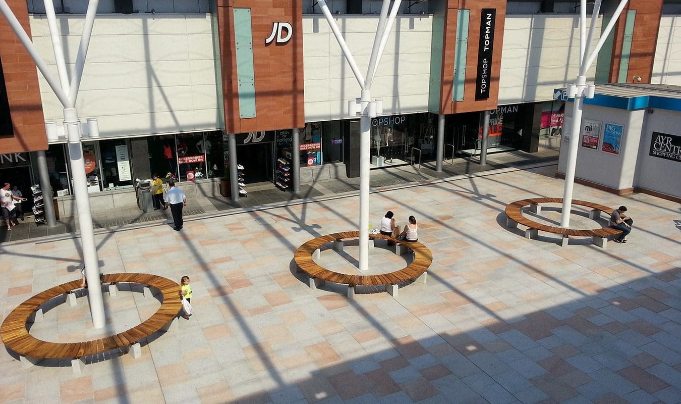 Full circle wooden benches with concrete feet around structural post