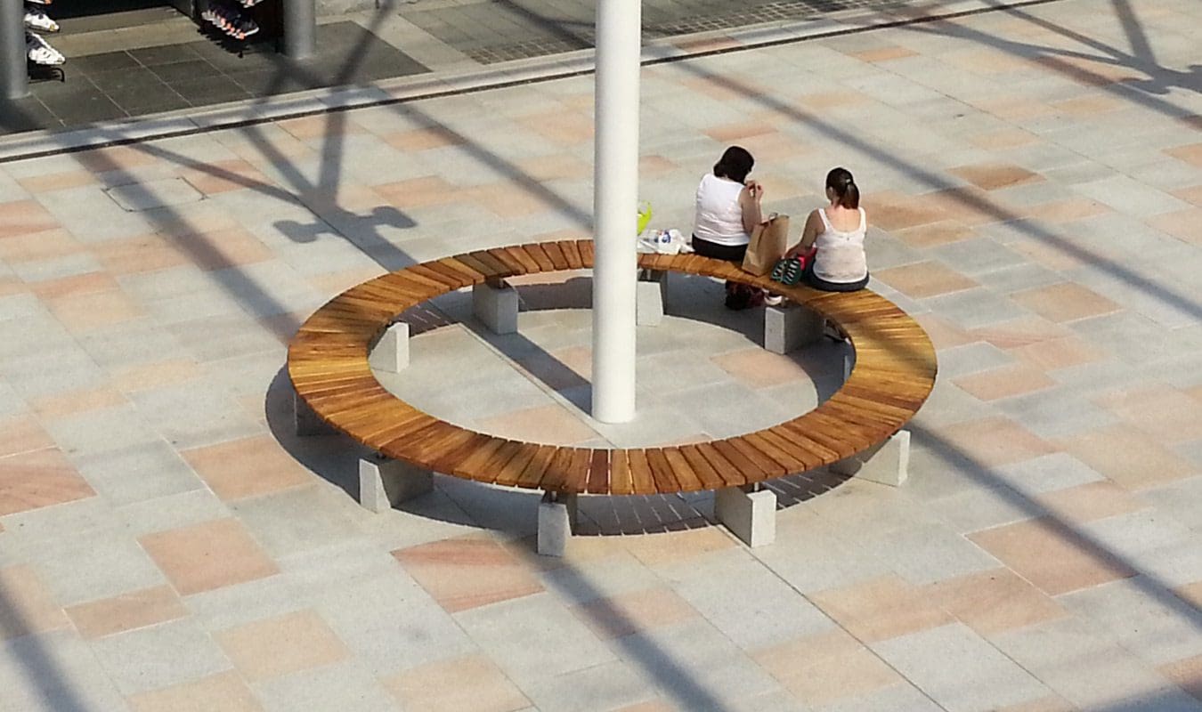 Full circle wooden benches with concrete feet around structural post