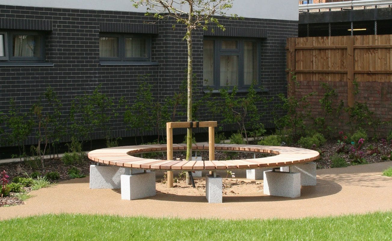 Wooden circle bench with concrete plinth legs around small tree outside