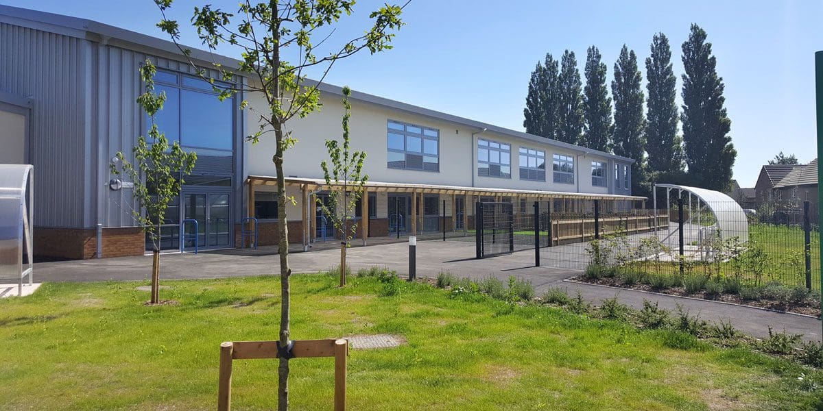 wide shot of school exterior showing wooden pergola and metal and plastic bike shelter