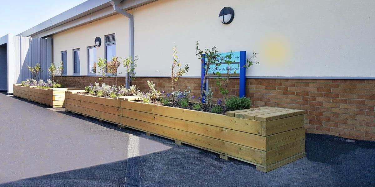 Long raised wooden planters with covered ends for seating