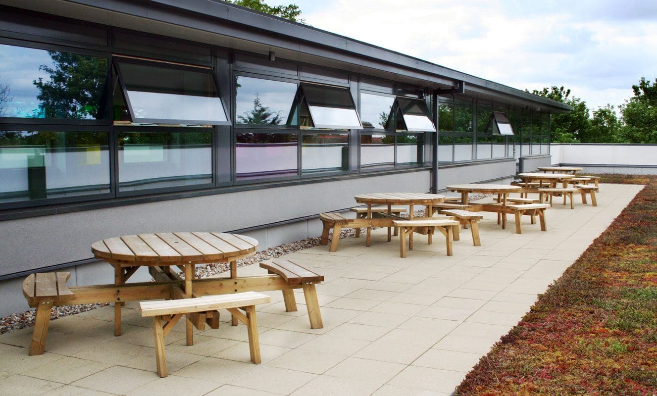 Row of outdoor circular wooden picnic tables and attached benches