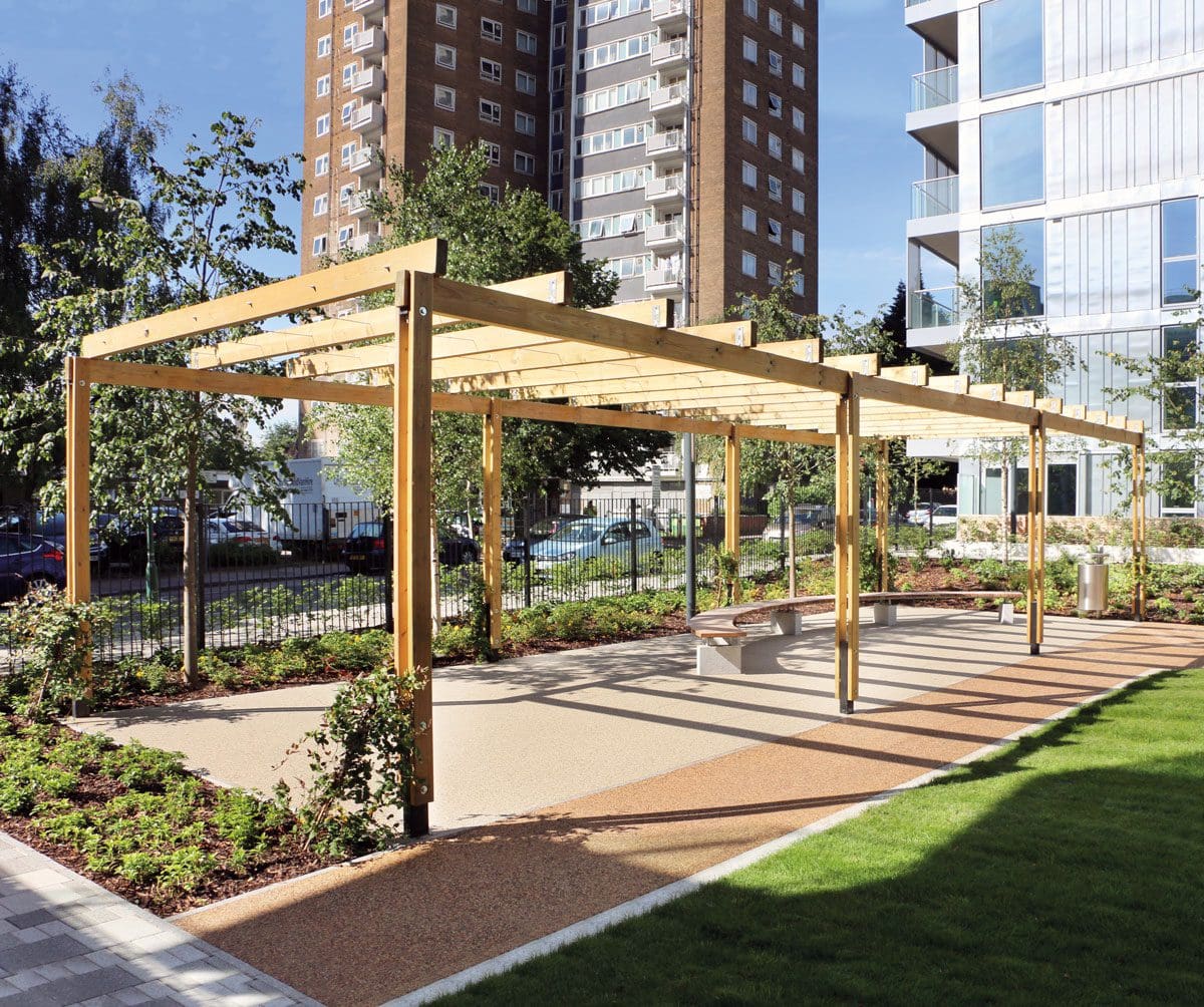 Wooden pergola over large wooden curved bench at the end of grassy area