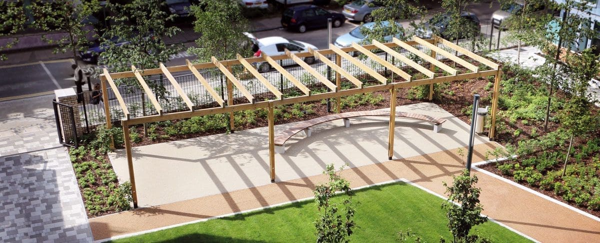 Wooden pergola over large wooden curved bench at the end of grassy area
