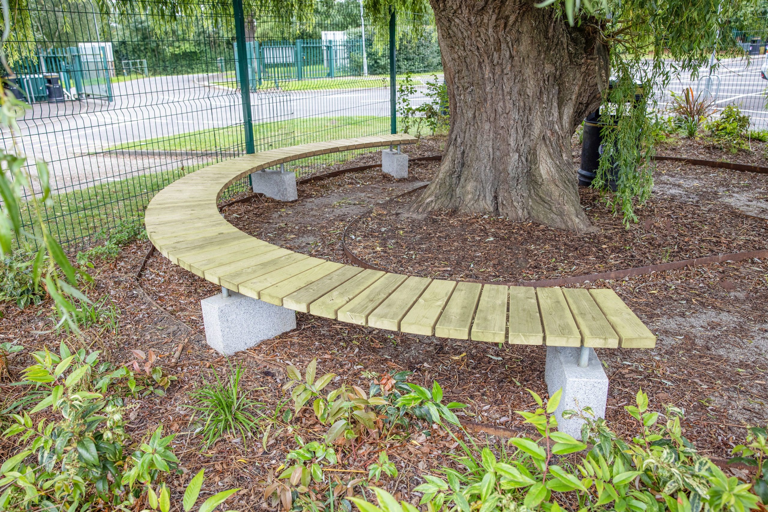 semi circle wooden bench with concrete feet around a large tree