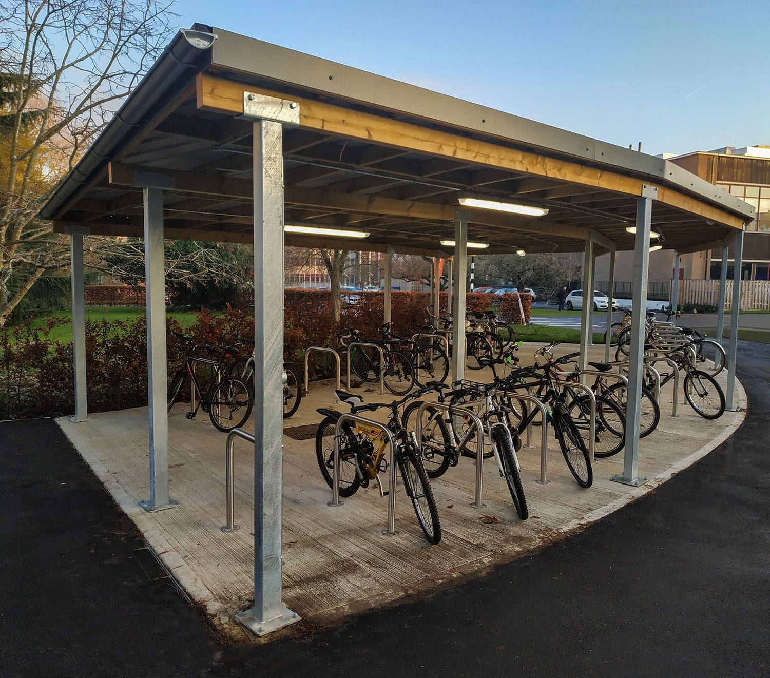 Rows of metal bike secure hoops under curved wooden and metal canopy