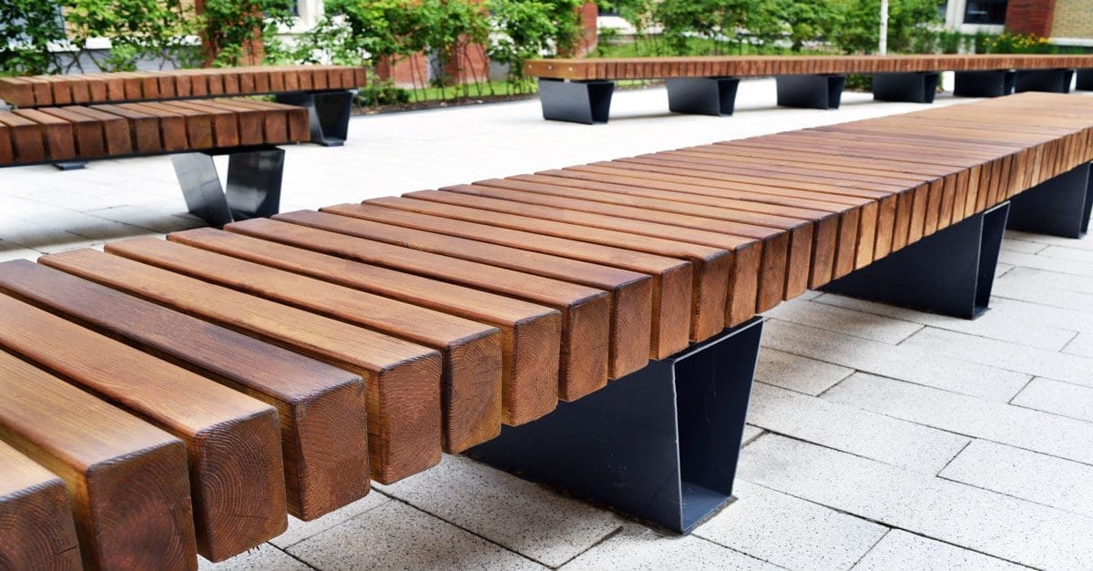Rows of wooden slatted dark brown bench with black metal triangular legs