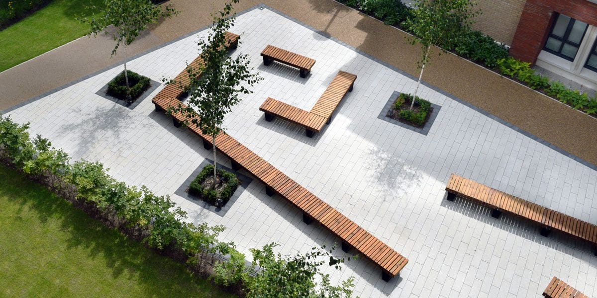 Birdseye view of university showing courtyard angular seating area of wooden benches with black metal legs