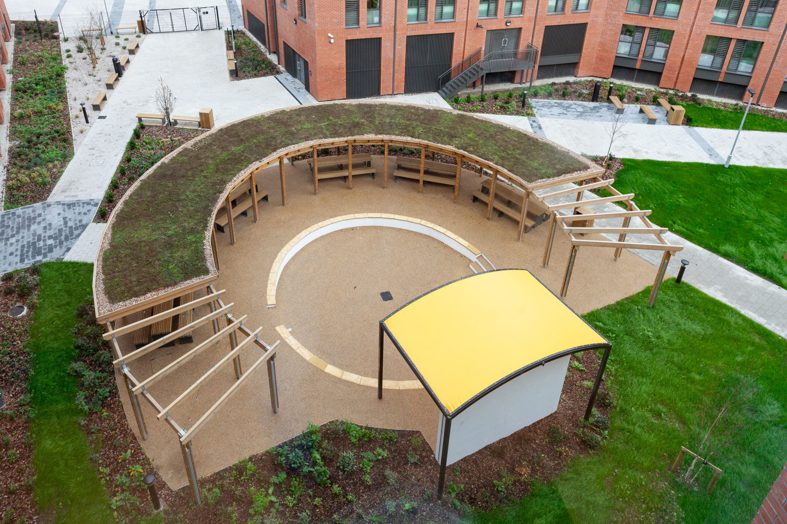 An aerial view of the new outdoor social area at Morriss House Student Accommodation with a curved wooden pergola topped with grass.